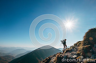 Boy backpacker traveler walk up on mountain top in contrast sun Stock Photo