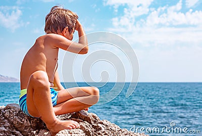 Boy on the beach stones. against the background of clear sea water Stock Photo