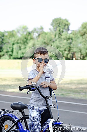 Boy with bicycle drinks bottled water Stock Photo