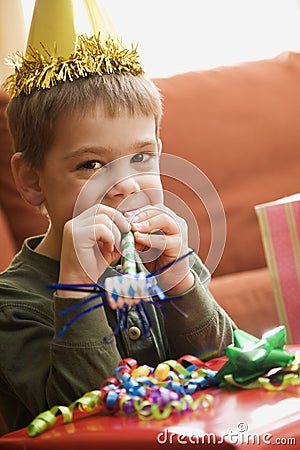 Boy blowing noisemaker. Stock Photo