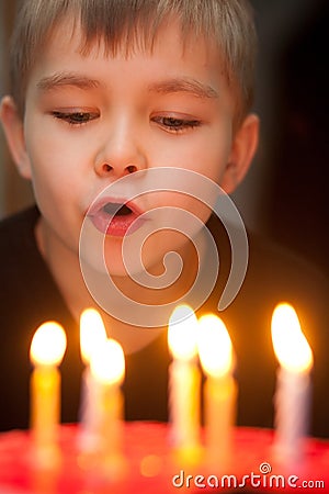Boy blowing out candles on birthday cake Stock Photo