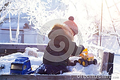 A boy in a bright orange hat plays with toys in a snowy winter Park Stock Photo