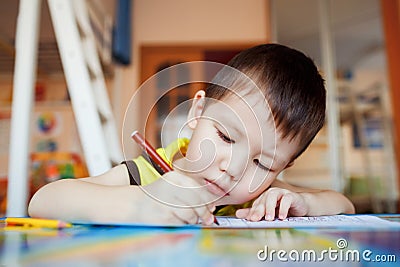 The boy carefully and intently draws in a special Stock Photo