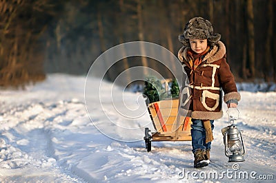 Boy with a Christmas tree in the winter forest. Stock Photo