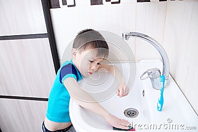 Boy cleaning in bathroom wash sink, child doing up housework helping mother with sanitary cleanness of home Stock Photo