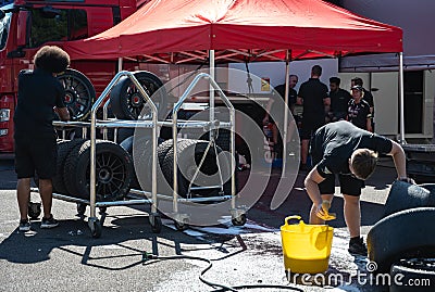 Boy cleaning slick racing tires with a sponge, soap and water Editorial Stock Photo