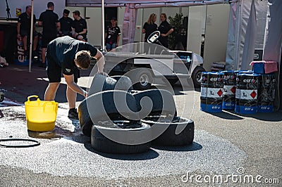 A boy cleaning slick racing tires with a sponge Editorial Stock Photo