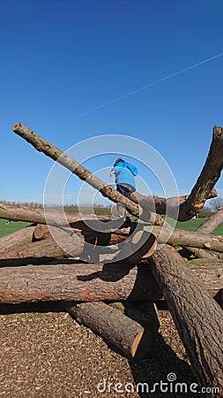 Boy climbing over tree logs Stock Photo