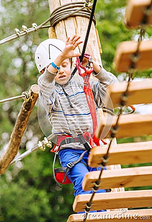 Boy climbing rope-ladder in adrenalin park Stock Photo