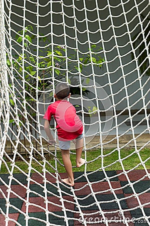 Boy climbing a rope net on the playground. Stock Photo