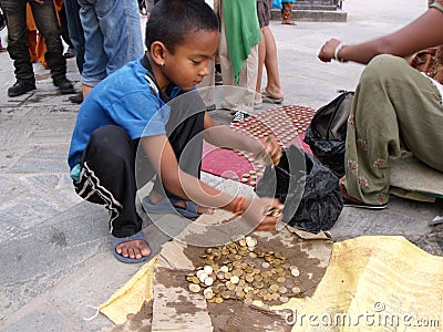 A boy collects coins for tourists to throw into a fountain at Swayambhunath Temple, the monkey temple. Kathmandu, Nepal Editorial Stock Photo