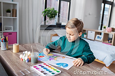 boy with colors and brush drawing picture at home Stock Photo