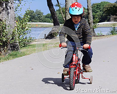 Boy Concentrating on Riding Bike with Training Whe Stock Photo