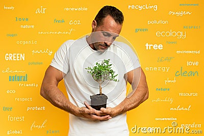 Boy cradles a small tree ready to be planted. yellow color background. concept of forestation, ecology and conservation Stock Photo