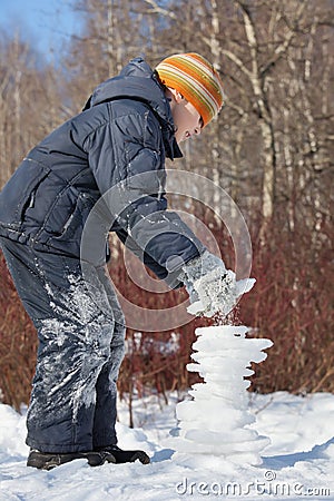 Boy creates pyramid from ice in day in winter Stock Photo