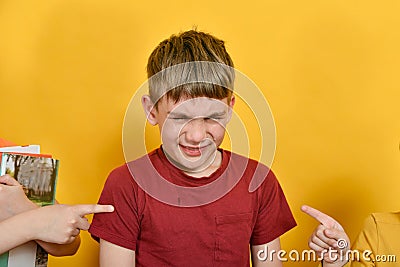 The boy is crying and does not want to study, friends with books poke fingers at him Stock Photo