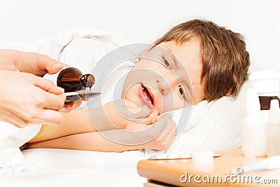Boy crying while mother pouring coughing syrup Stock Photo