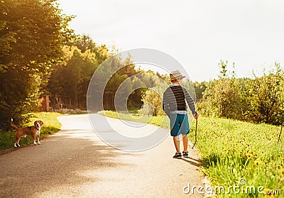 Boy and dog walk on contryside road at the evening summertime Stock Photo