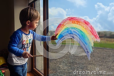 Boy drawing rainbow on the window Stock Photo