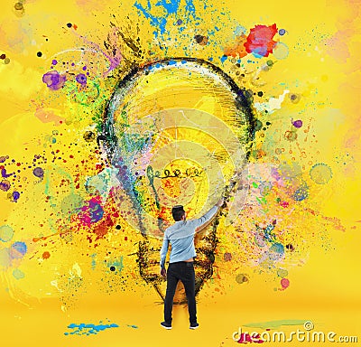 Boy draws with a brush a big light bulb. Concept of innovation and creativity. Yellow style Stock Photo