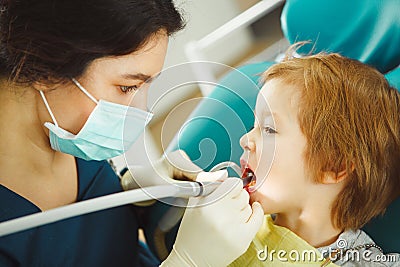 Boy drills the tooth of female dentist. Little child on dental chair. Stock Photo