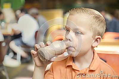 Boy drinking chocolate milk during lunch at his school cafeteria Stock Photo