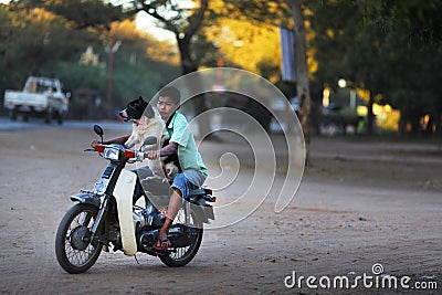 Boy driving a motorcycle with his dog in Bago, Myanmar Editorial Stock Photo