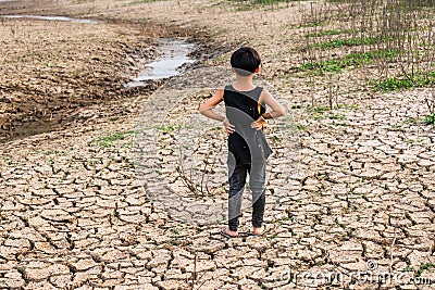 Boy in dryland looking at drought landscape. Concept for climate change from global worming. Stock Photo