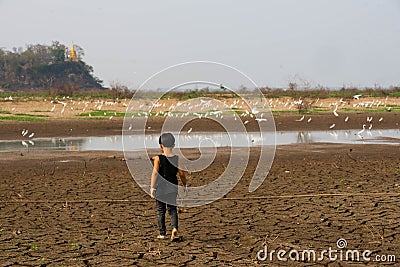 Boy in dryland looking at drought landscape. Concept for climate change from global worming. Stock Photo