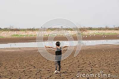 Boy in dryland looking at drought landscape. Concept for climate change from global worming. Stock Photo
