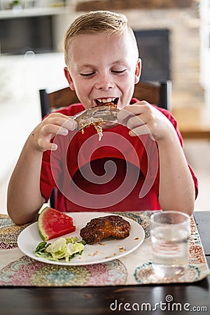 Boy eating a delicious plate of Barbecue ribs, watermelon and salad Stock Photo