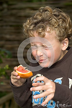 Boy eating Sour Grapefruit Stock Photo
