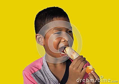 The boy eats hot dog Happily Isolated on a yellow background. Embed clipping path. Junk food concept Stock Photo