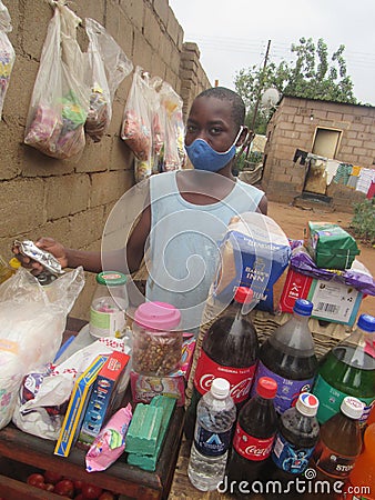 Child wearing facemask selling goods at a backyard grocery stall Editorial Stock Photo