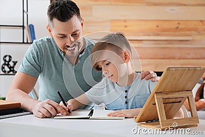 Boy with father doing homework at table Stock Photo