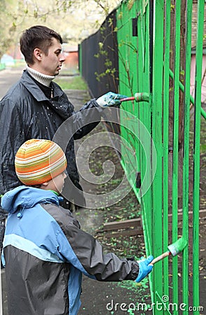 Boy and father stand back and dye fence Stock Photo