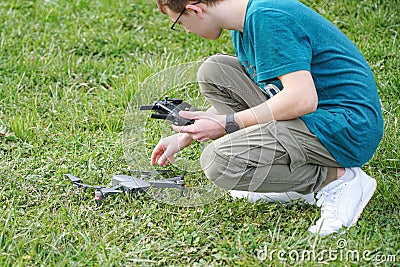A boy in a field launches a quadcopter and controls it from the remote control Stock Photo