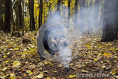 A boy in the forest is lighting a fire. Concept: lost in the forest, survival in the wild, lost without parents, a young traveler, Stock Photo