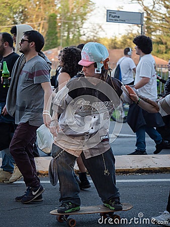 Boy with Funny Hat and Rasta Hair and with Joint Playing with his Skateboard during a Street Rave Party Editorial Stock Photo