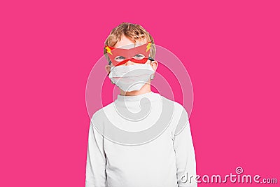 A boy with funny superhero mask to protect himself from viral infections of the disease, isolated on pink background Stock Photo