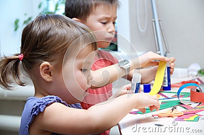 Boy and girl cutting paper for craft, brother and sister playing Stock Photo