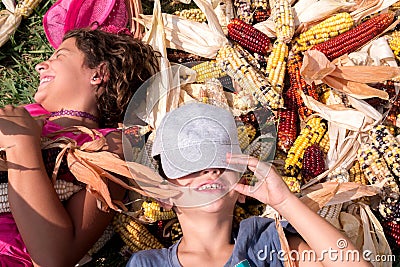 Boy and girl having fun surrounded by colorful corncobs Stock Photo