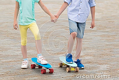 Boy and girl hold hands and want to ride skateboards together Stock Photo