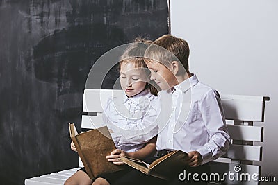 Boy and girl from primary school class on the bench read books o Stock Photo
