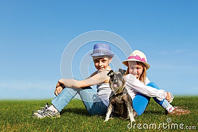 Boy and girl sitting back to back on the grass on a summer day Stock Photo