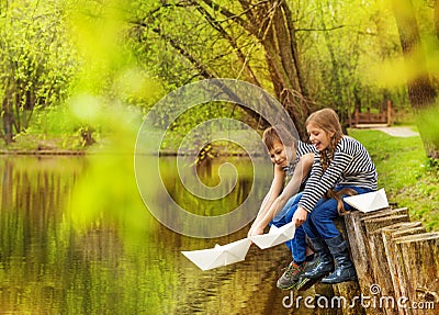 Boy and girl in striped shirts play paper boats Stock Photo