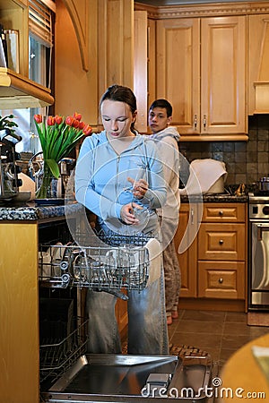 boy girl teenagers unload the dishwasher in the house in the kitchen help at home brother sister friends Classmates Stock Photo