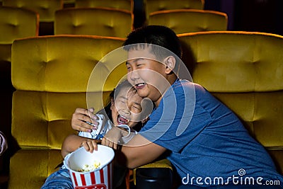 Boy and girl watching movie feeling scary and frightening at movie theater seats. The faces have feeling bad during film Stock Photo