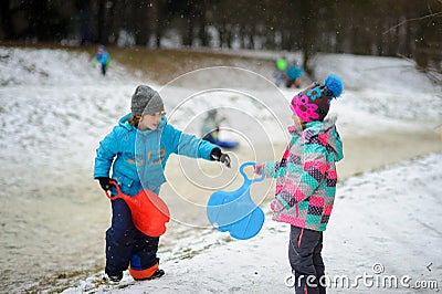 Boy and girl of younger school age in the winter park about slope for toboggans. Stock Photo