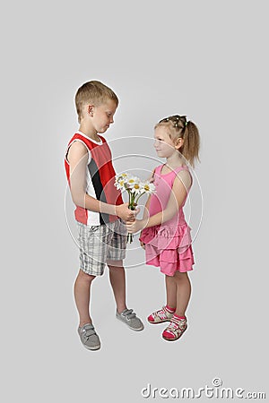 Boy gives girl bouquet of daisies on gray Stock Photo